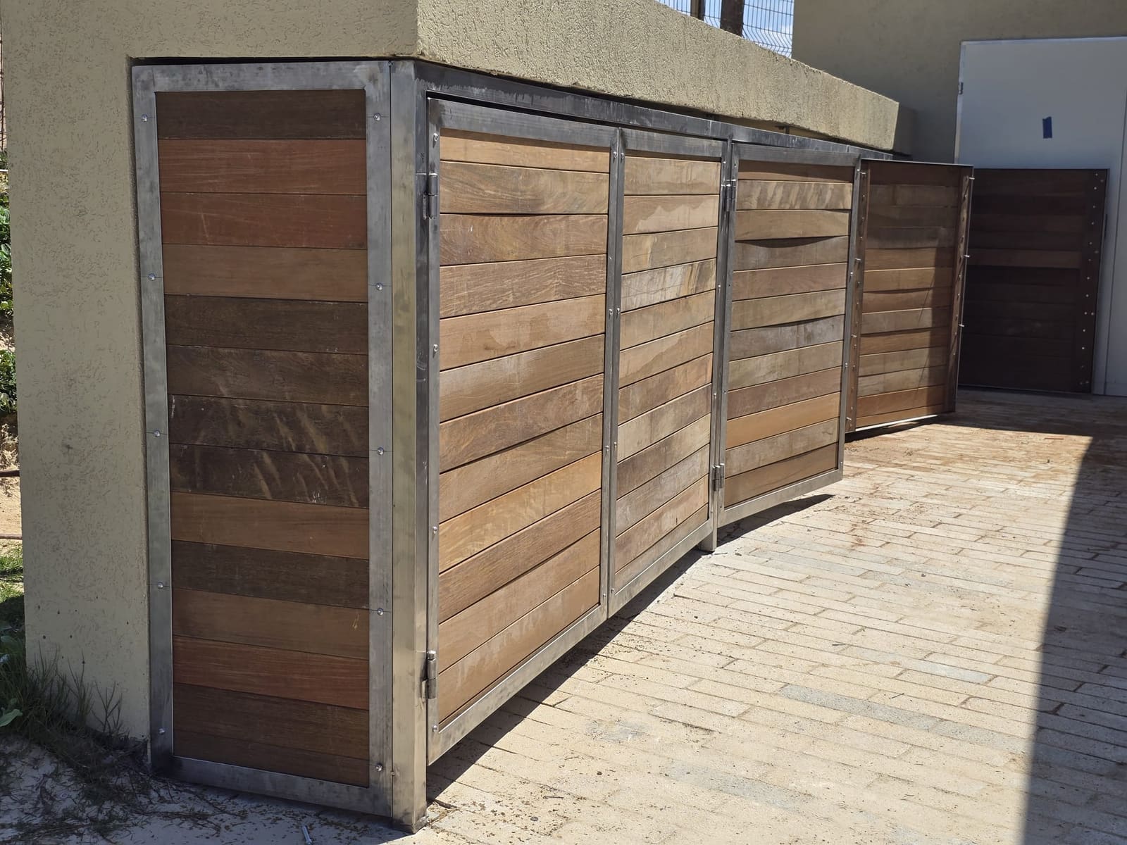 מסתור חדר משאבות מחופה עץ עם דלתות במסגרות נירוסטה במתקן חוף