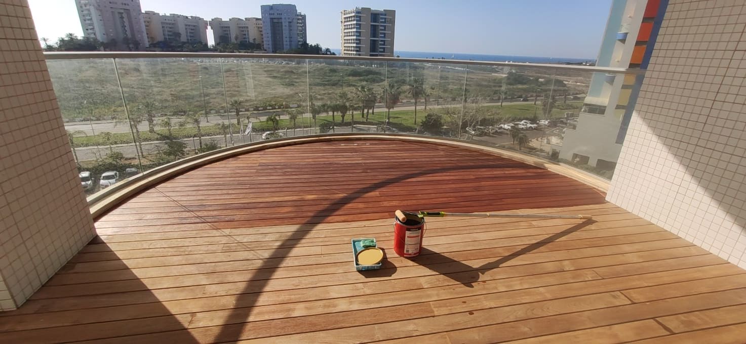 מרפסת קשתית עם מעקה זכוכית ונוף לים, מרכז הדק צבוע בגוון חם והשוליים עדיין בהירים