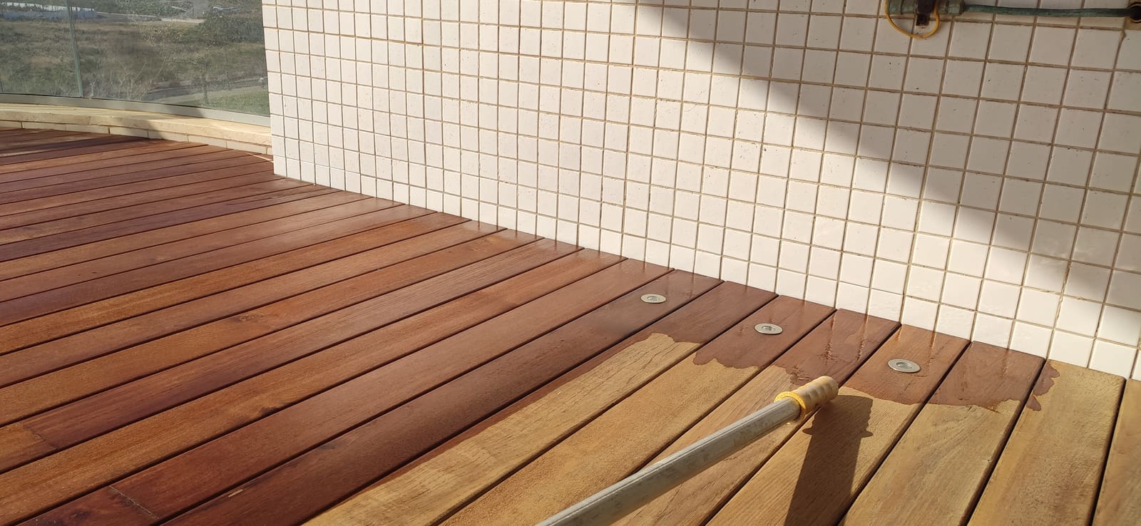 קו הגבול בין קרשים שכבר הוזנו בגוון כהה לקרשים בהירים, לצד קיר מחופה פסיפס לבן